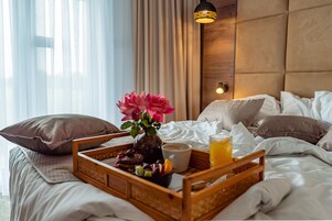 Una cama bien hecha con una bandeja de desayuno, que incluye una taza de café, un vaso de zumo de naranja y una variedad de pasteles.