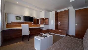 Una habitación de hotel moderna con una pared de acento de madera, un televisor de pantalla plana, un escritorio y un área de estar confortable.