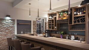 Un área de bar moderna con una pared de piedra, estantes de madera con botellas de vino y taburetes de bar.