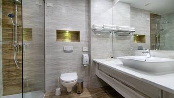 Un baño moderno con ducha envuelta en vidrio, inodoro, lavabo y toallero.