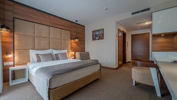 A modern bedroom with a large bed, bedside tables, a desk, and a wardrobe.