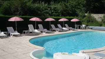 A swimming pool with lounge chairs and striped umbrellas.