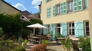 A courtyard with outdoor seating, a table, and chairs. - Hotel Restaurant d'Orfeuil (Bourbonne-les-Bains)