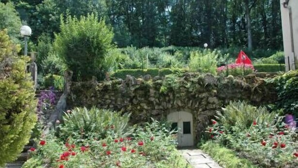 A garden with a stone wall, red flowers, and various plants. - Hotel Restaurant d'Orfeuil (Bourbonne-les-Bains)