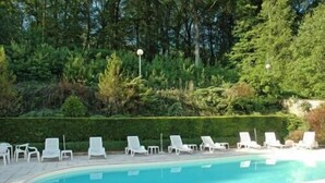 A swimming pool with white lounge chairs and a hedge in the background. - Hotel Restaurant d'Orfeuil (Bourbonne-les-Bains)