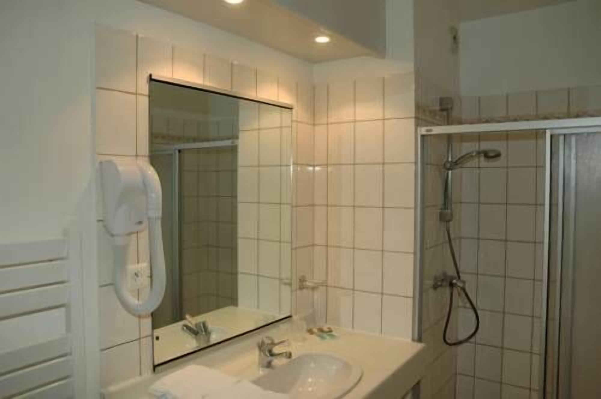 A bathroom with a sink, mirror, and shower.