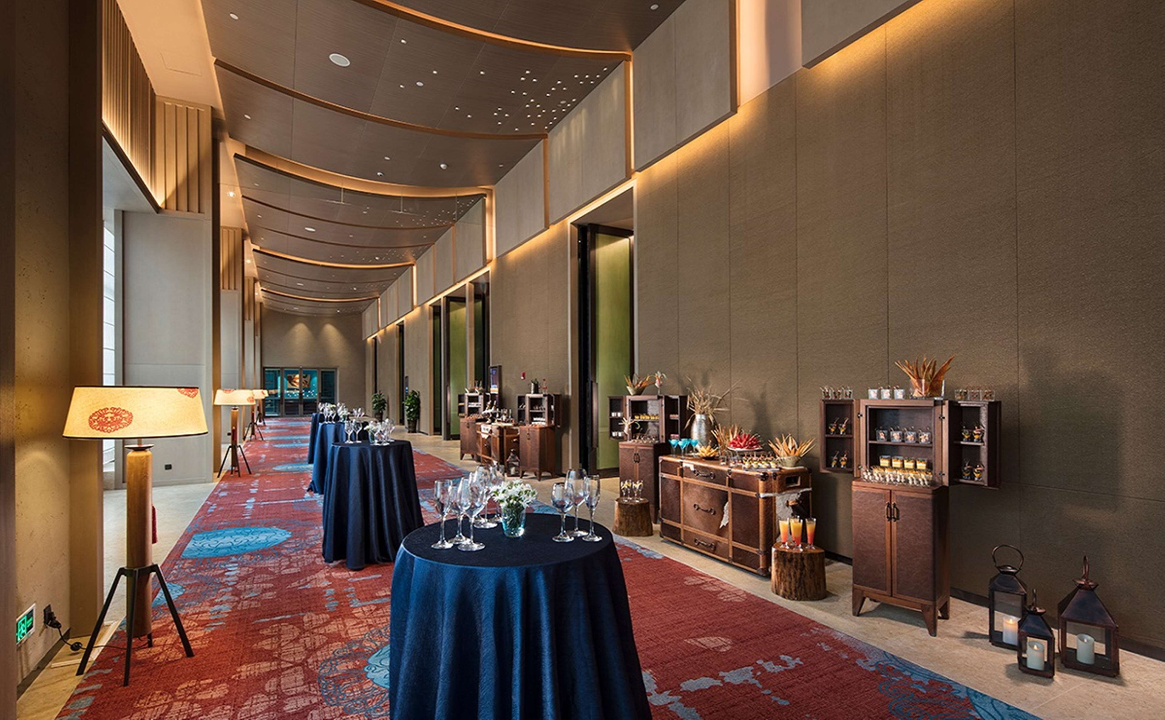 A long corridor with tables set up for dining, a reception area with a lamp, and various decorative items on shelves.