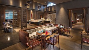 Un restaurante moderno con zona de estar central, mesas de madera y barra.