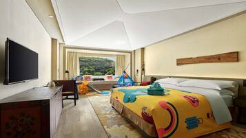 Habitación de hotel con una cama grande, televisión de pantalla plana, escritorio y ventana con vistas a zonas verdes.