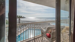 Un balcón con piscina, sillas de descanso y vista al mar.