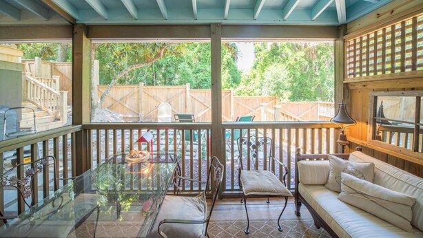 A covered patio with a glass table, cushioned seating, and a view of a backyard. - Erie The 213 E Hideaway 1 Bedroom Holiday Home By My Ocean Rentals (Folly Beach)