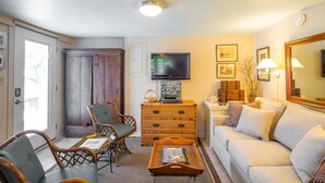 A living room with a sofa, two chairs, a television, a wooden cabinet, and a fireplace. - Erie The 213 E Hideaway 1 Bedroom Holiday Home By My Ocean Rentals (Folly Beach)