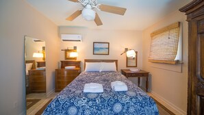 A hotel room with a bed, a ceiling fan, a nightstand, a mirror, and a window with a view of the ocean. - Erie The 213 E Hideaway 1 Bedroom Holiday Home By My Ocean Rentals (Folly Beach)