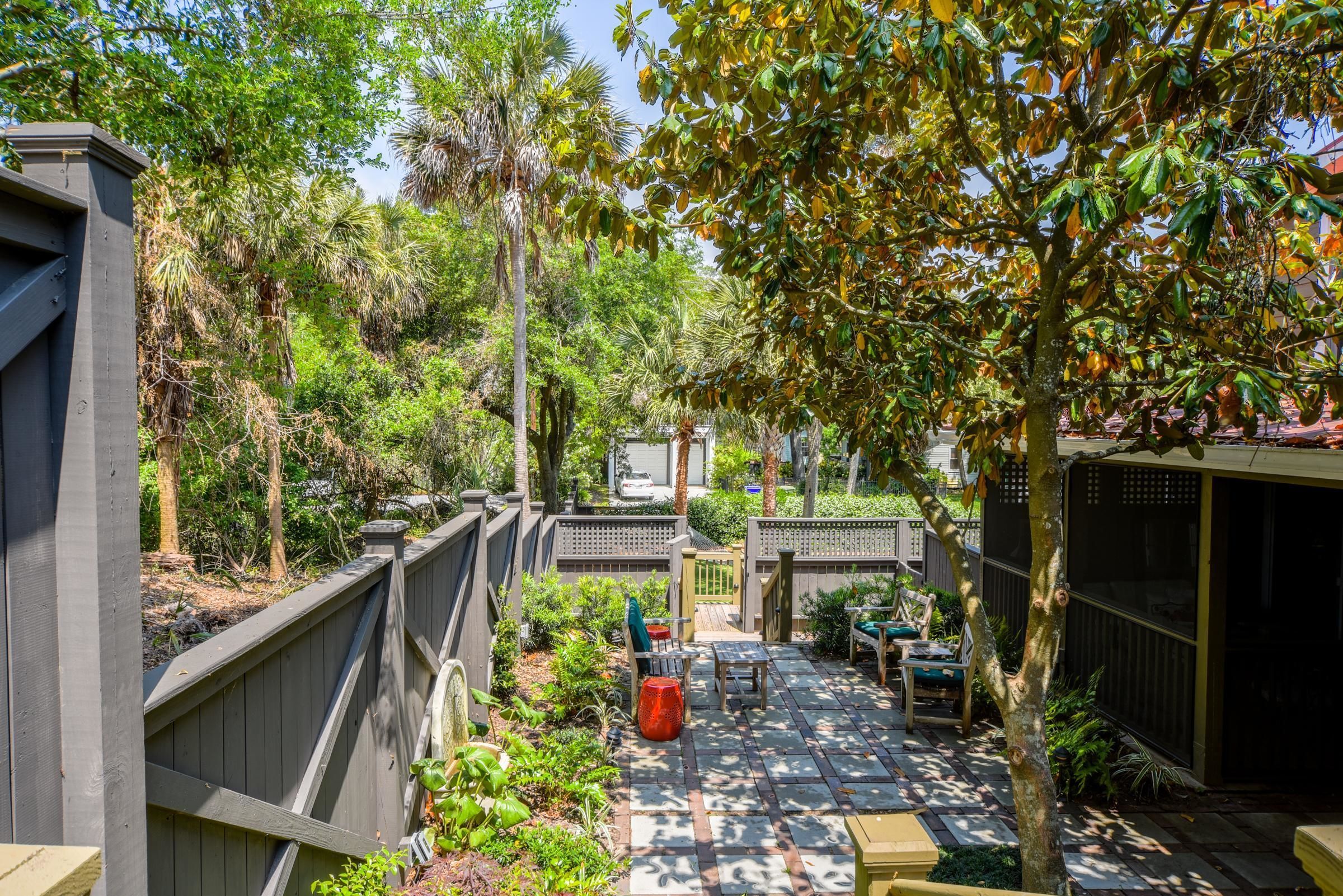 A patio area with a wooden deck, seating, and a view of a residential street.