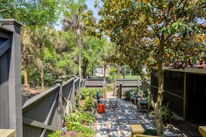 A patio area with a wooden deck, seating, and a view of a residential street.