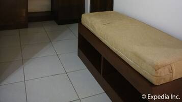 A room with a bed, a wardrobe, a television mounted on the wall, and a door.
