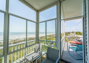 A balcony with a view of the beach and ocean.