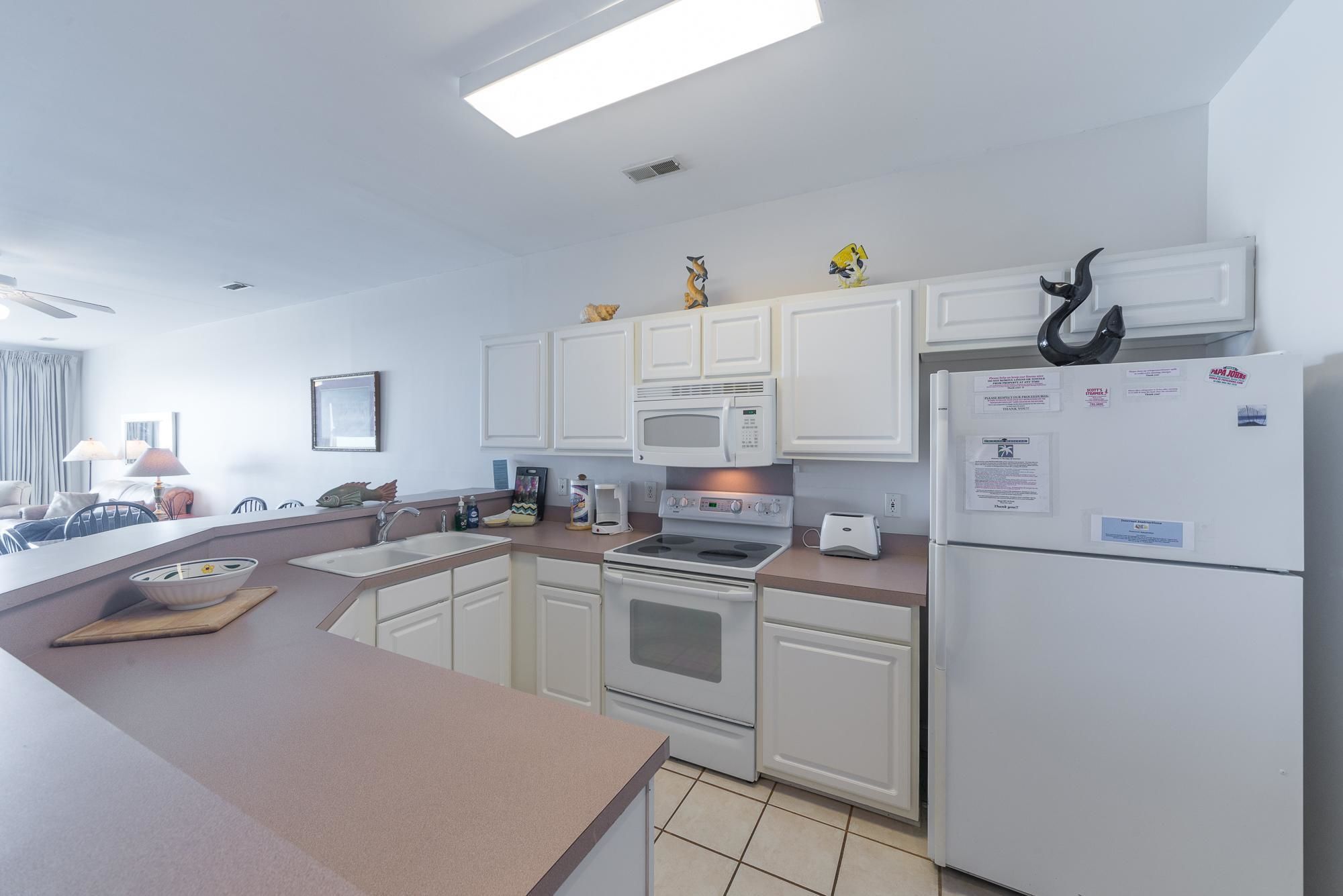 A modern kitchen with white cabinets, a microwave, an oven, and a refrigerator.