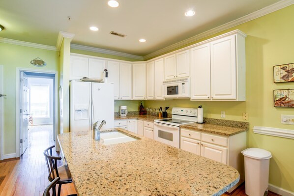 A kitchen with white cabinets, granite countertops, a refrigerator, stove, and microwave. - TURTLE BAY 23 3 Bedroom Holiday Home By My Ocean Rentals (Folly Beach)