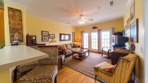 A living room with a dining table, chairs, sofas, a TV, and a ceiling fan. - Marsh Winds 2A 3 Bedroom Holiday Home By My Ocean Rentals (Folly Beach)