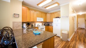 A kitchen with wooden cabinets, granite countertops, and stainless steel appliances. - Marsh Winds 2A 3 Bedroom Holiday Home By My Ocean Rentals (Folly Beach)