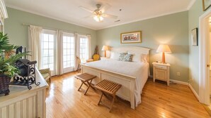 A bedroom with a large bed, two bedside tables with lamps, a ceiling fan, and a window with curtains. - Marsh Winds 2A 3 Bedroom Holiday Home By My Ocean Rentals (Folly Beach)
