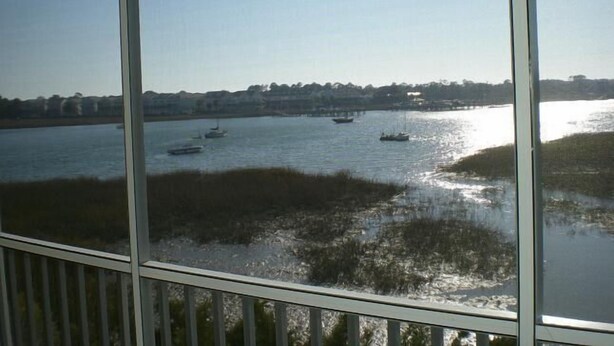 A view of a river with boats, a distant shoreline with buildings, and a clear sky. - Turn of the River 2G 3 Bedroom Holiday Home By My Ocean Rentals (Folly Beach)