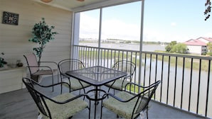A covered patio with a table and chairs, a ceiling fan, a potted plant, and a view of a body of water and buildings. - Turn of the River 2G 3 Bedroom Holiday Home By My Ocean Rentals (Folly Beach)