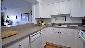 A kitchen with white cabinets, a dishwasher, a wooden cutting board, and a sink. - Turn of the River 2G 3 Bedroom Holiday Home By My Ocean Rentals (Folly Beach)