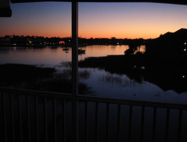 A view of a lake at dusk with boats and a distant shoreline.