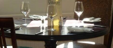 A round dining table with two wine glasses, a menu stand, and a vase.