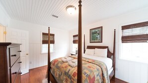A bedroom with a four-poster bed, a dresser with drawers, a painting on the wall, and a window with blinds. - E Huron 308 4 Bedroom Holiday Home By My Ocean Rentals (Folly Beach)