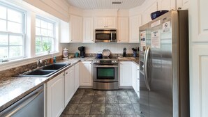 A modern kitchen with white cabinets, stainless steel appliances, and a granite countertop. - E Huron 308 4 Bedroom Holiday Home By My Ocean Rentals (Folly Beach)