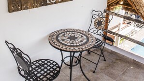 A wooden sign with a message, a round metal table, two chairs, and a thatched roof structure.
