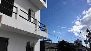 A modern building with a white facade, multiple windows, and a balcony.
