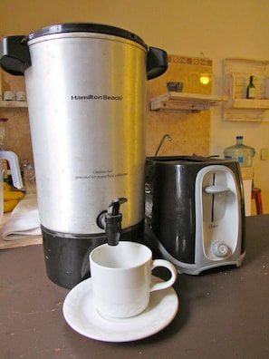 Una cafetera Hamilton Beach, un tostador y una taza blanca sobre una encimera de cocina.