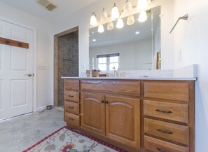 Une salle de bain avec un meuble-lavabo en bois, un grand miroir et un espace douche.