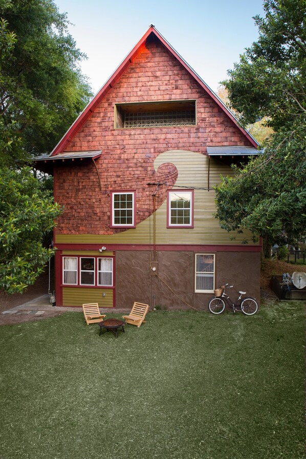 A two-story house with a sloped roof, a garage, and a small front yard with a lawnmower and a bicycle.