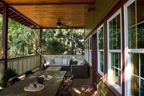 A covered outdoor seating area with a wooden table, chairs, and a sofa.