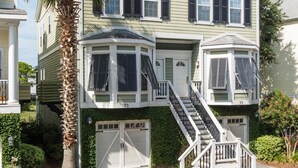 A two-story house with a bay window, a covered front porch, and a staircase leading to the upper level. - Waters Edge Community 95 3 Bedroom Holiday Home By My Ocean Rentals (Folly Beach)