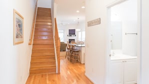 A staircase leading to a dining area with wooden flooring and a white door on the right. - Waters Edge Community 95 3 Bedroom Holiday Home By My Ocean Rentals (Folly Beach)