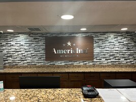 Un mostrador de recepción con un cartel que dice 'AmericInn by Wyndham' y un quiosco digital.