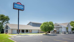 Ein Hotel mit der Beschriftung "AmericInn Lodge & Suites", das ein modernes Gebäude mit  überdachtem Eingang und einem Parkplatz zeigt.