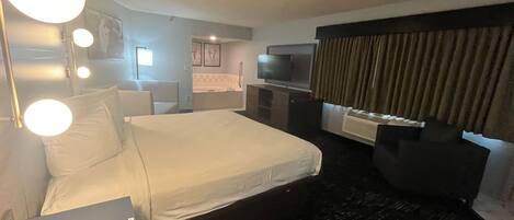 Una habitación de hotel con cama, escritorio, televisión y baño.