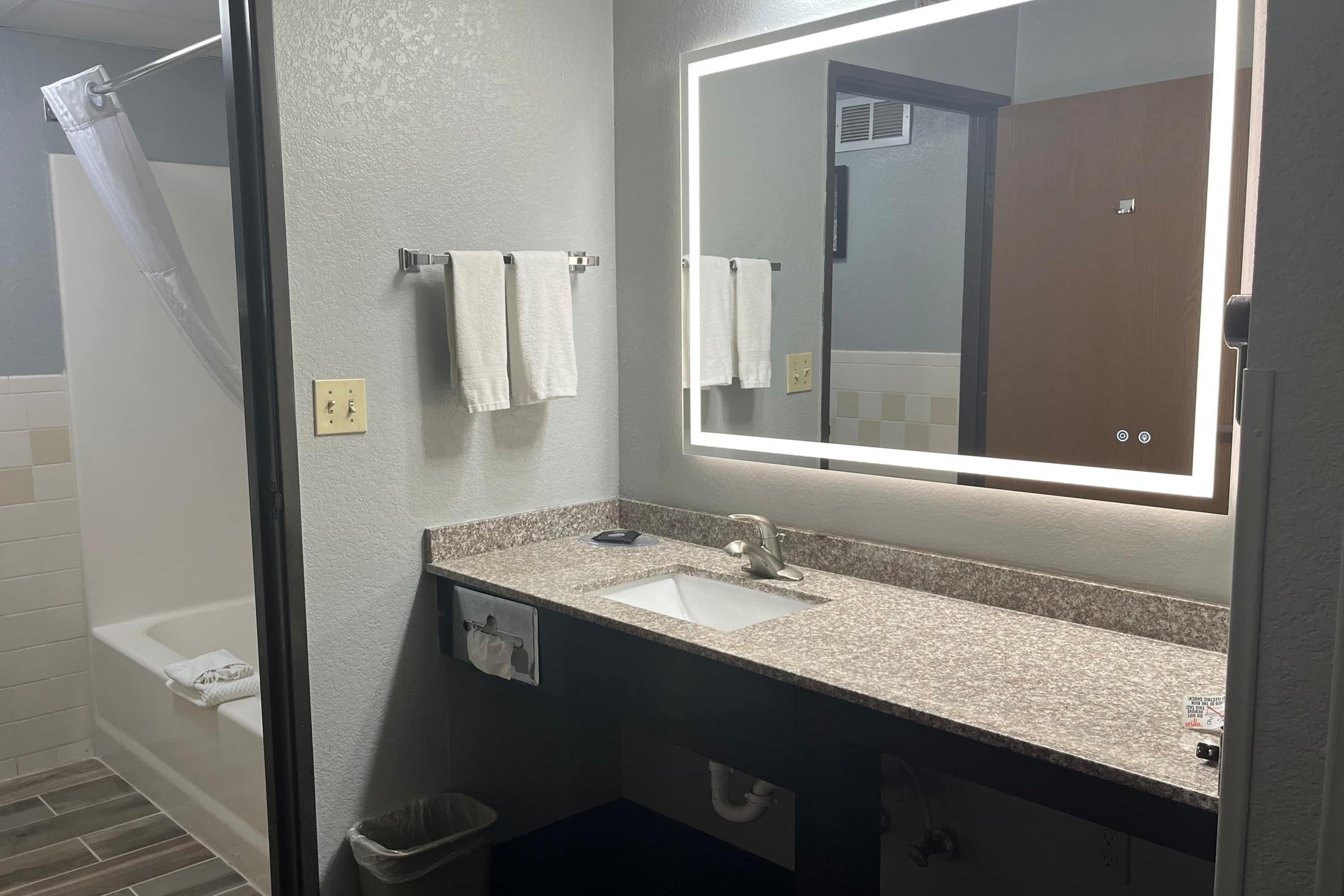 A bathroom with a sink, mirror, towel rack, and shower.