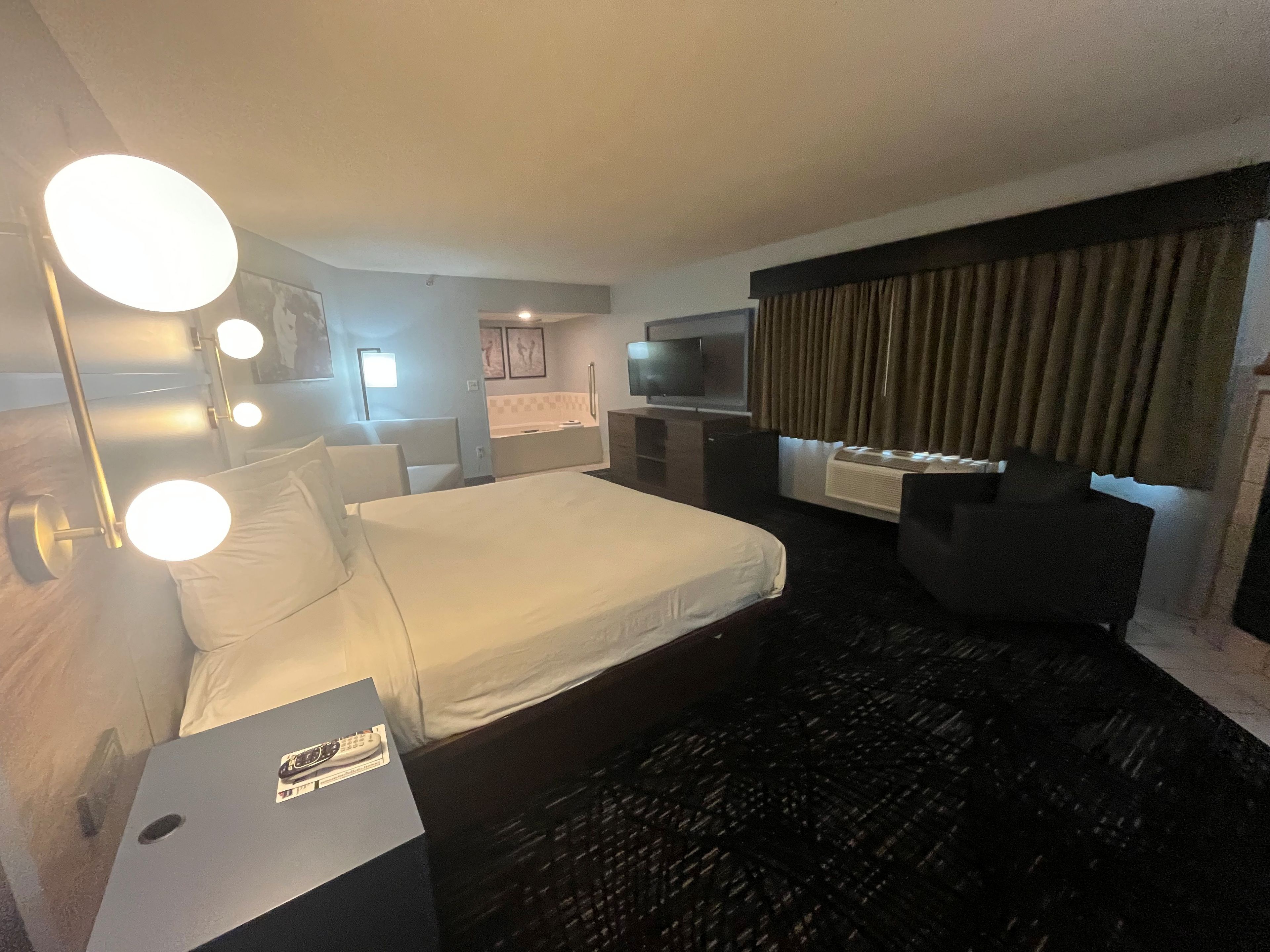A hotel room with a bed, a desk, a TV, and a bathroom.