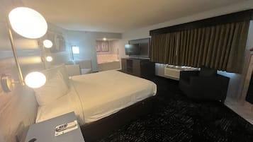 A hotel room with a bed, a desk, a TV, and a bathroom.
