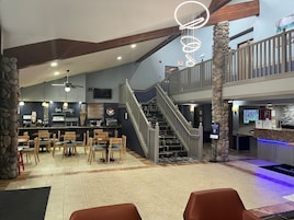 Un restaurante con bar, varias zonas de estar y una escalera que conduce a un nivel superior.