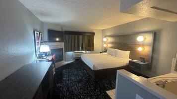 Una habitación de hotel con cama, escritorio, silla y baño con bañera.