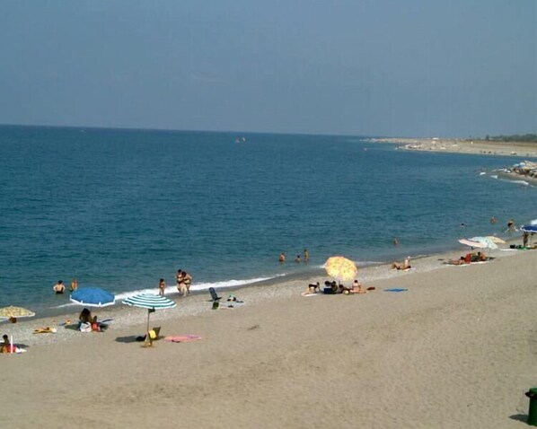 A beach with people sunbathing and swimming.
